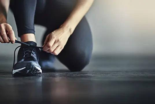 En kvinnlig löpare knyter skorna