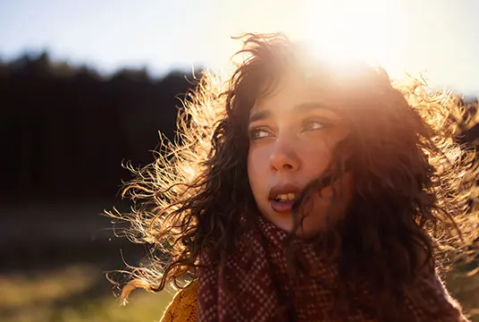 Kvinna i solsken tittar bort.