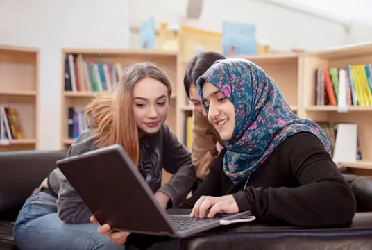 Tre studenter på ett bibliotek