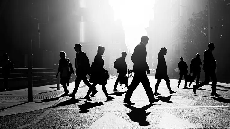 svart-vit bild i motljus med människor som går över ett övergångsställe