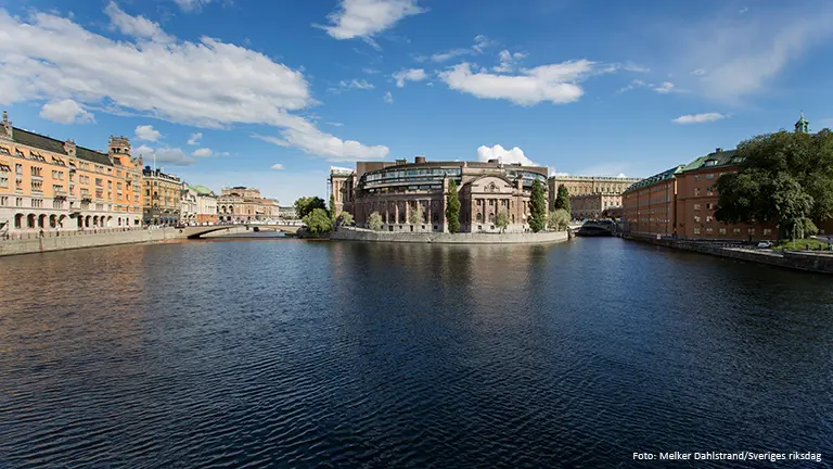 Västra riksdagshuset speglas i Strömmen. Till vänster i bild syns Rosenbad. Foto: Melker Dahlstrand/Sveriges riksdag.
